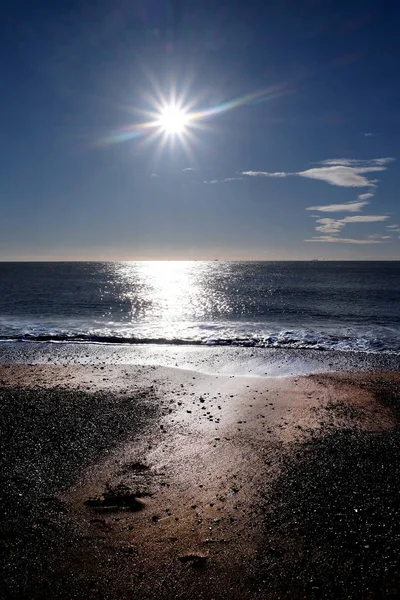 Sonne am blauen Himmel wirft lange Glanzlichter über Meer und Strand — Stockfoto