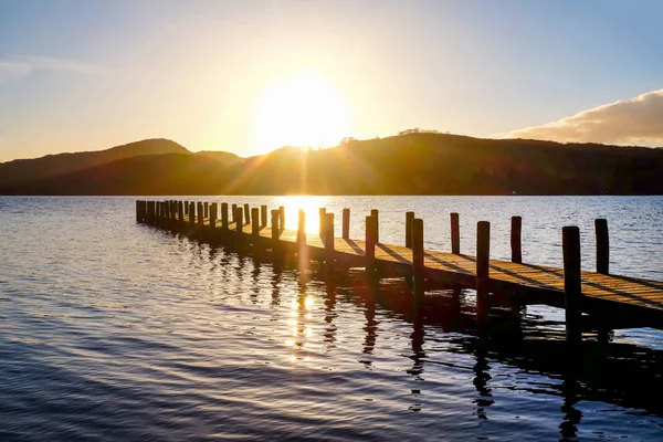 very long wooden jetty, jutting out into a calm blue wooden lake