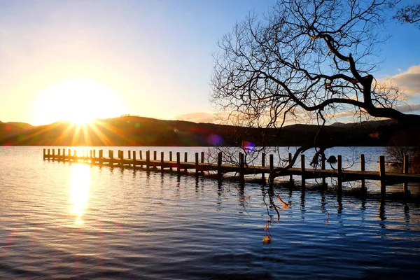 Muelle de madera muy largo, sobresaliendo en un tranquilo lago de madera azul — Foto de Stock