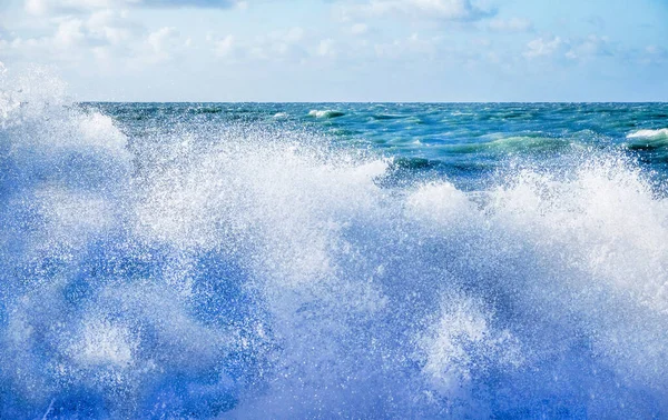 Spray de mar branco de uma onda quebrando na praia com um mar agitado — Fotografia de Stock