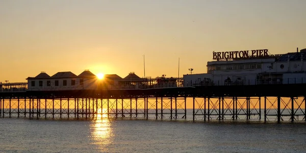 Brighton Pier glühend gelb bei Sonnenuntergang erstreckt sich in die cal s — Stockfoto