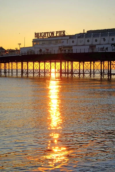 Brighton Pier glöder gul med solnedgången under den — Stockfoto