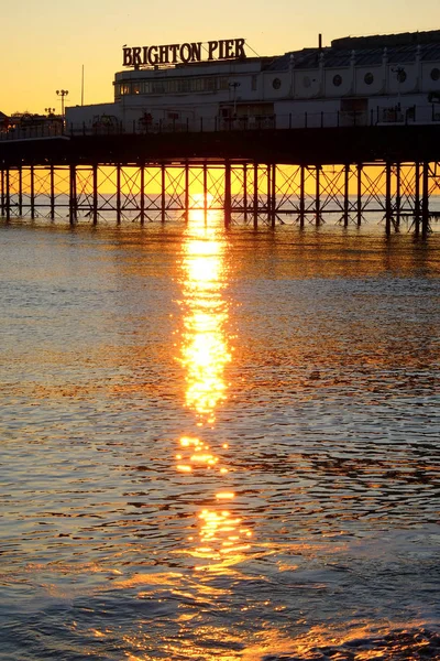 Brighton Pier glöder gul med solnedgången under den — Stockfoto