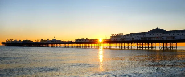 Brighton Palace Pier glödande gul med solnedgången under — Stockfoto
