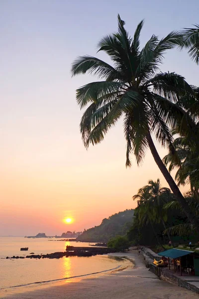 Uma baía tropical com um mar calmo e palmeiras brilhando vermelho no Imagem De Stock