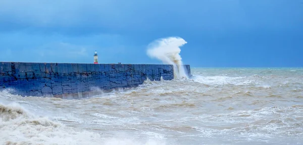 Uma parede de porto com um mar áspero que bate contra ele e uma luz — Fotografia de Stock