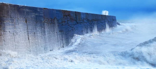 Un muro portuario con un mar rudo que se estrella contra él. —  Fotos de Stock