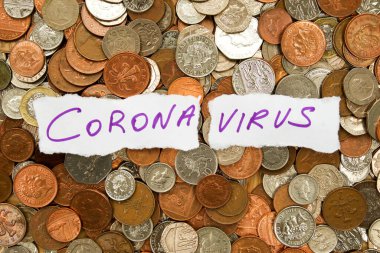 Yüzlerce gümüş ve bakır madeni paranın üzerinde mor mürekkeple yazılmış iki parça beyaz kağıt üzerinde Corona virüsü yazılıydı. İngiliz parası sterlindi, yatay formattı.