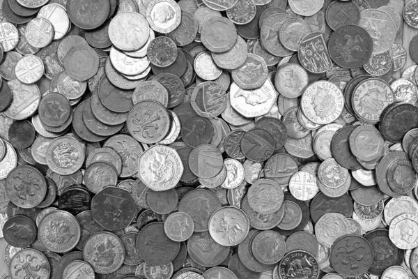 UK currency, hundreds of British copper and silver colored coins randomly piled ontop of each other, one pound coins, fifty pence, twenty pence, two pence, one pence,