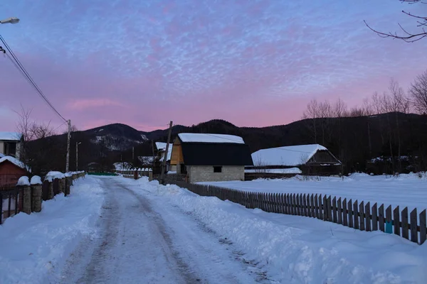 Kış köyünde mor gün batımı. Ukrayna, İvano-Frankivsk bölgesi, Guta köyü.