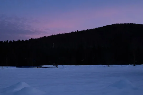 Kış köyünde mor gün batımı. Ukrayna, İvano-Frankivsk bölgesi, Guta köyü.