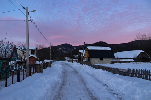 Kış köyünde mor gün batımı. Ukrayna, İvano-Frankivsk bölgesi, Guta köyü.