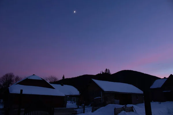 Kış köyünde mor gün batımı. Ukrayna, İvano-Frankivsk bölgesi, Guta köyü.