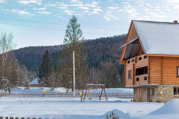 Evde, bacası ve dumanı olan bir evde, ağaçların arasında. Ukrayna, İvano-Frankivsk bölgesi, Guta köyü.