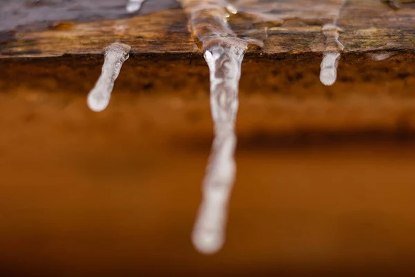 Tahta bir çatıdan buz saçağı süzülüyor.