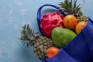 Sıfır atık konsepti, taze tropikal meyveli mavi alışveriş tekstil çantası: mango, ananas, ejderha ve tutku meyvesi