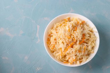 Açık mavi arka planda havuçlu ev yapımı lahana turşusu, mayalanmış yiyecek, üst manzara.