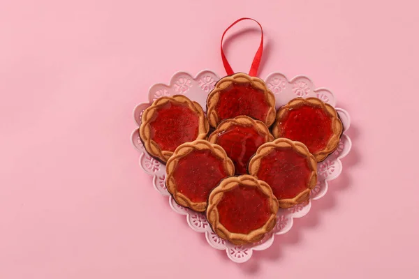 Ciasteczka z dżemem jagodowym na talerzu w kształcie serca na Walentynki na różowym tle — Zdjęcie stockowe