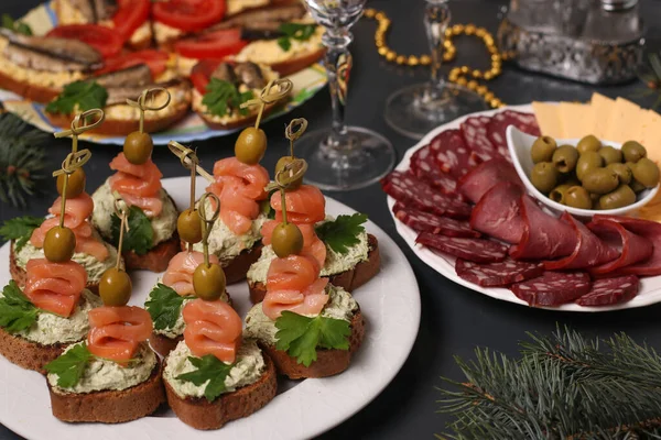 El aperitivo a la mesa de fiesta - los canapés con el salmón, los bocadillos con los espadines y el queso en rodajas y la salchicha — Foto de Stock