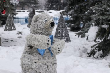 Açık hava parkındaki parlak çelenklerden gelen beyaz ayı, çocuklar için bir dinlenme alanı tasarlıyor.
