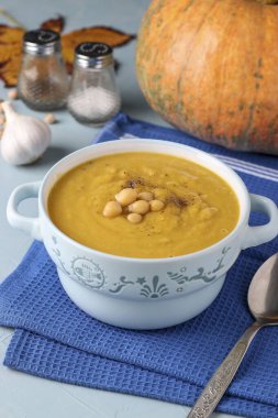 Açık mavi arka planda nohutlu vejetaryen sonbahar balkabağı kreması çorbası.