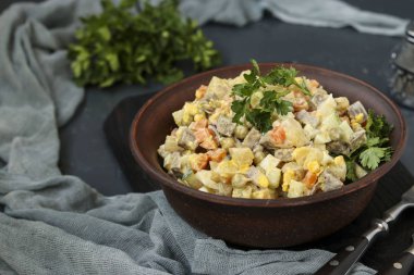 Geleneksel Rus şenlik salatası Olivier 'in dili bir kâsede koyu arka planda, yatay yönelimde.