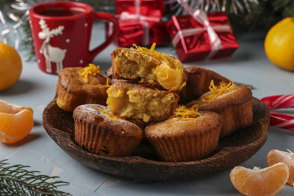 Homemade muffins with tangerines, sprinkled with powdered sugar is located on the New Year's or Christmas light blue background — Stock Photo, Image