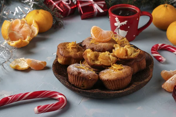 Homemade muffins with tangerines, sprinkled with powdered sugar is located on the New Years or Christmas light blue background — Stock Photo, Image