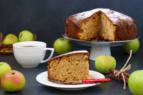 Пирог с яблоками, корицей и имбирем на темном фоне, с кусочком торта и чашкой кофе на переднем плане — стоковое фото