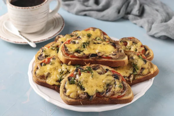 Sandwiches calientes con tomates, champiñones y queso sobre un fondo azul claro con una taza de café, orientación horizontal —  Fotos de Stock