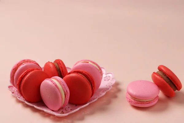 Deliciosos macaroons doces em uma placa figural em um fundo rosa, macaroons vermelhos e rosa, Conceito para o Dia dos Namorados, 8 de março e Dia das Mães — Fotografia de Stock