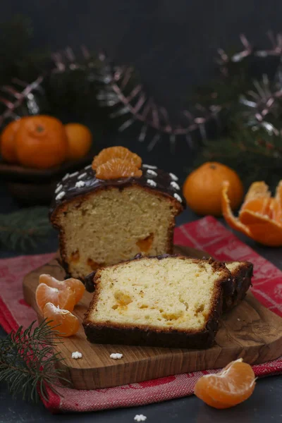 Кекс с мандаринами, покрытые шоколадной глазурью расположен на фоне Нового года, вертикальная ориентация — стоковое фото