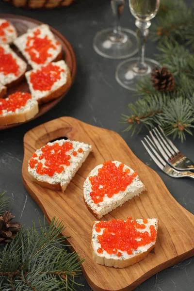 Sandvișurile cu caviar roșu sunt situate pe o placă de lemn pe un fundal întunecat. Gustare festivă — Fotografie, imagine de stoc