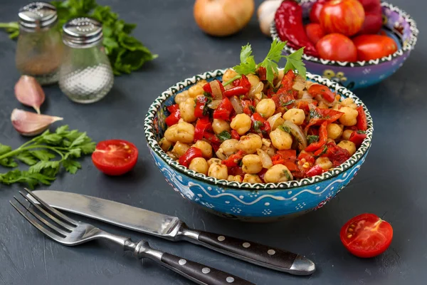 Гарнир из гороха с перцем и помидорами, вегетарианское блюдо, богатое белком, расположенное в тарелке на темном фоне горизонтально — стоковое фото
