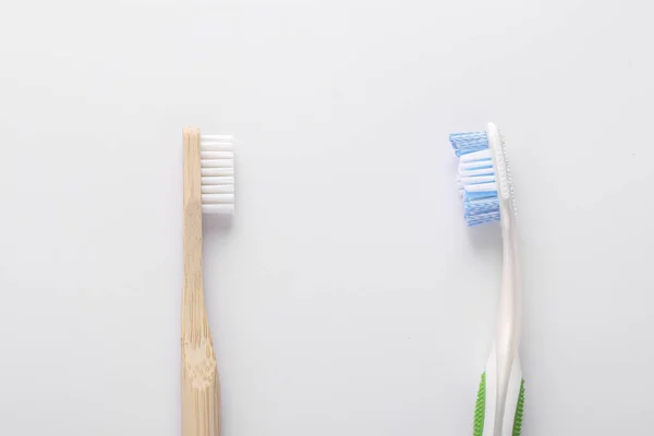 Zero waste concept, Eco wooden toothbrush vs plastic toothbrush on white background: Reduce, Reuse and Recycle concept. Flat lay, Closeup, Horizontal orientation — Stock Photo, Image