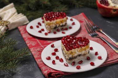 Koyu arkaplanda nar tohumlarıyla süslenmiş kalp şeklinde katmanlı şenlikli salata, yatay yönelim.