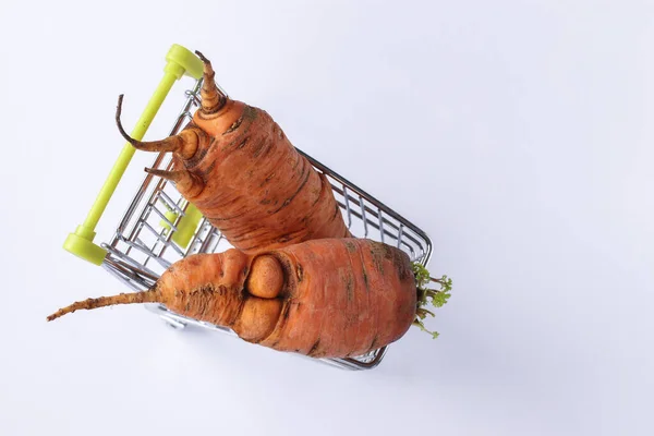 Carro de comestibles con fea zanahoria sobre fondo blanco. Concepto compras ambientales, Comida ecológica — Foto de Stock