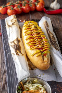 Sosisli sosisli sandviç koyu bir arka plan, rustik tarzı, dikey yönelim karşı ahşap bir tahta üzerinde yer almaktadır