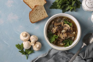 Şampiyon mantar çorbası ve mercimek beyaz bir tabakta açık mavi arka planda, üst manzara
