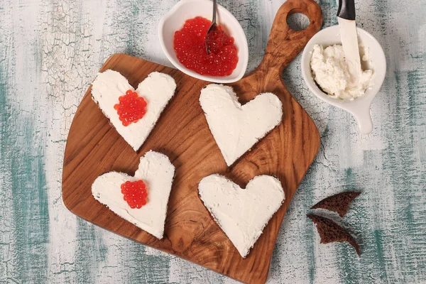 Gotowanie kanapek z czerwonym kawiorem i serem śmietankowym w kształcie serca na Walentynki — Zdjęcie stockowe