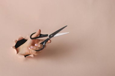 Kadın elinin makasları pembe kağıtta yuvarlak bir deliktedir, boşluğu kopyala, kapat