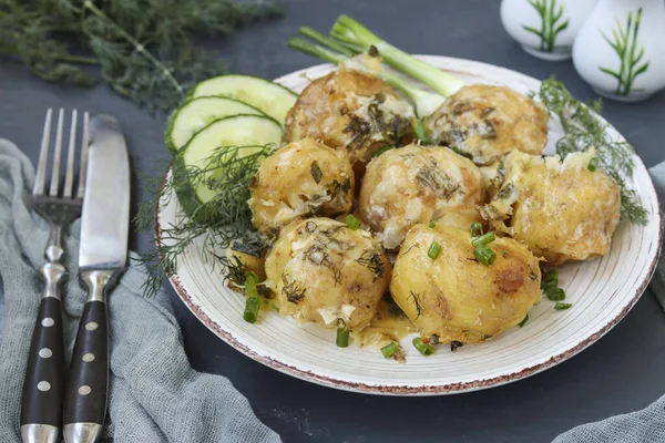 Baked young potatoes with cheese in a plate against a dark background — Zdjęcie stockowe