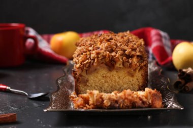 Yulaf ezmeli, elmalı ve mısır gevrekli ev yapımı kek. Arka planda metal tepside yulaf ezmesi. Yakın plan.