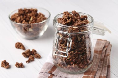 Çikolata taneli gevrek müsli, doğal bal ve fındıklı cam kavanozda beyaz arka plan, sağlıklı yemek, yakın plan, yatay format...