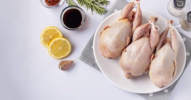 Beyaz arka planda beyaz bir plaka üzerinde üç taze organik bıldırcın, boşluğu kopyala, Üst Manzara