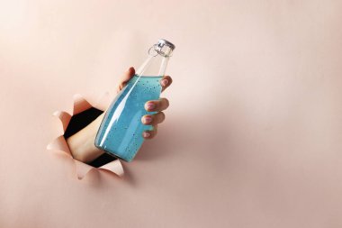 Fesleğen tohumlu mavi bir içecek ya da kadın eliyle pembe kağıtta yuvarlak bir delikten geçen fındık tohumları, kopyalama alanı, yakın çekim