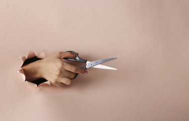 Kadın el, makasları pembe kağıttaki yuvarlak delikten geçirip uzayı kopyalayacak.