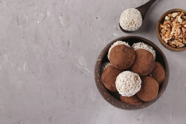 Boules d'énergie de noix et flocons d'avoine avec flocons de noix de coco et cacao dans un bol de noix de coco sur fond gris, format horizontal, Vue du dessus — Photo