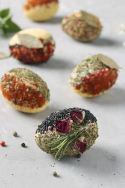 Paskalya yumurtalarının çeşitli baharat ve mısır gevrekleri ile birlikte gri beton arka planda, dikey formatta ve yakın planda boya ve koruyucu içermeyen eko-tasarımı.