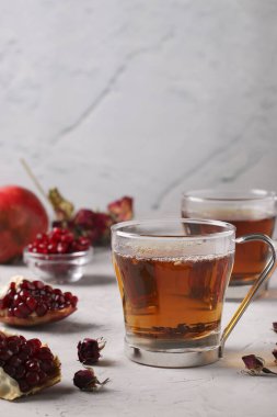 Gri beton zemin üzerinde iki şeffaf fincanda nar çayı, dikey format, metin için yer